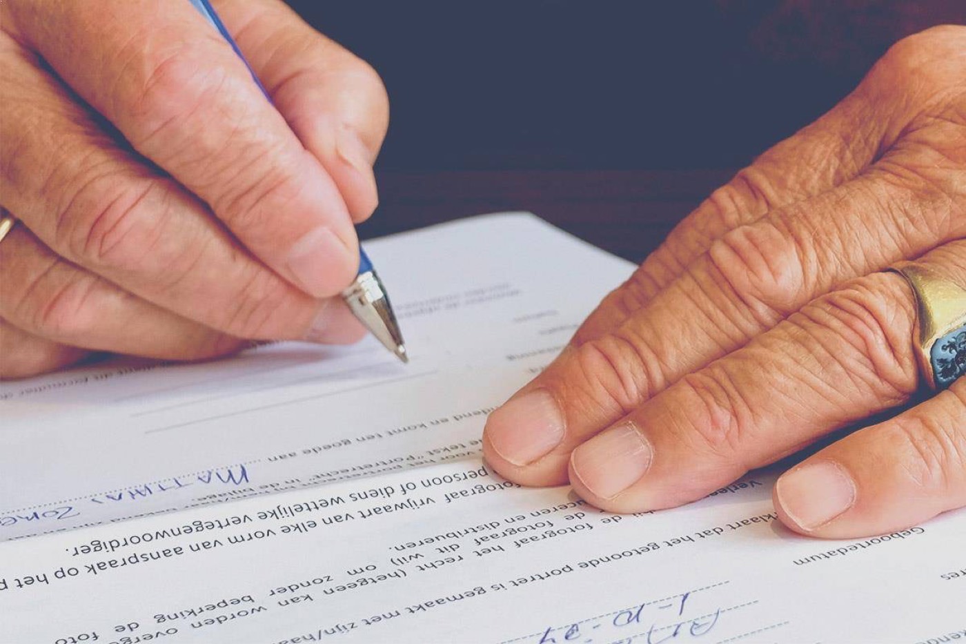 An older person signing a document with a notary present