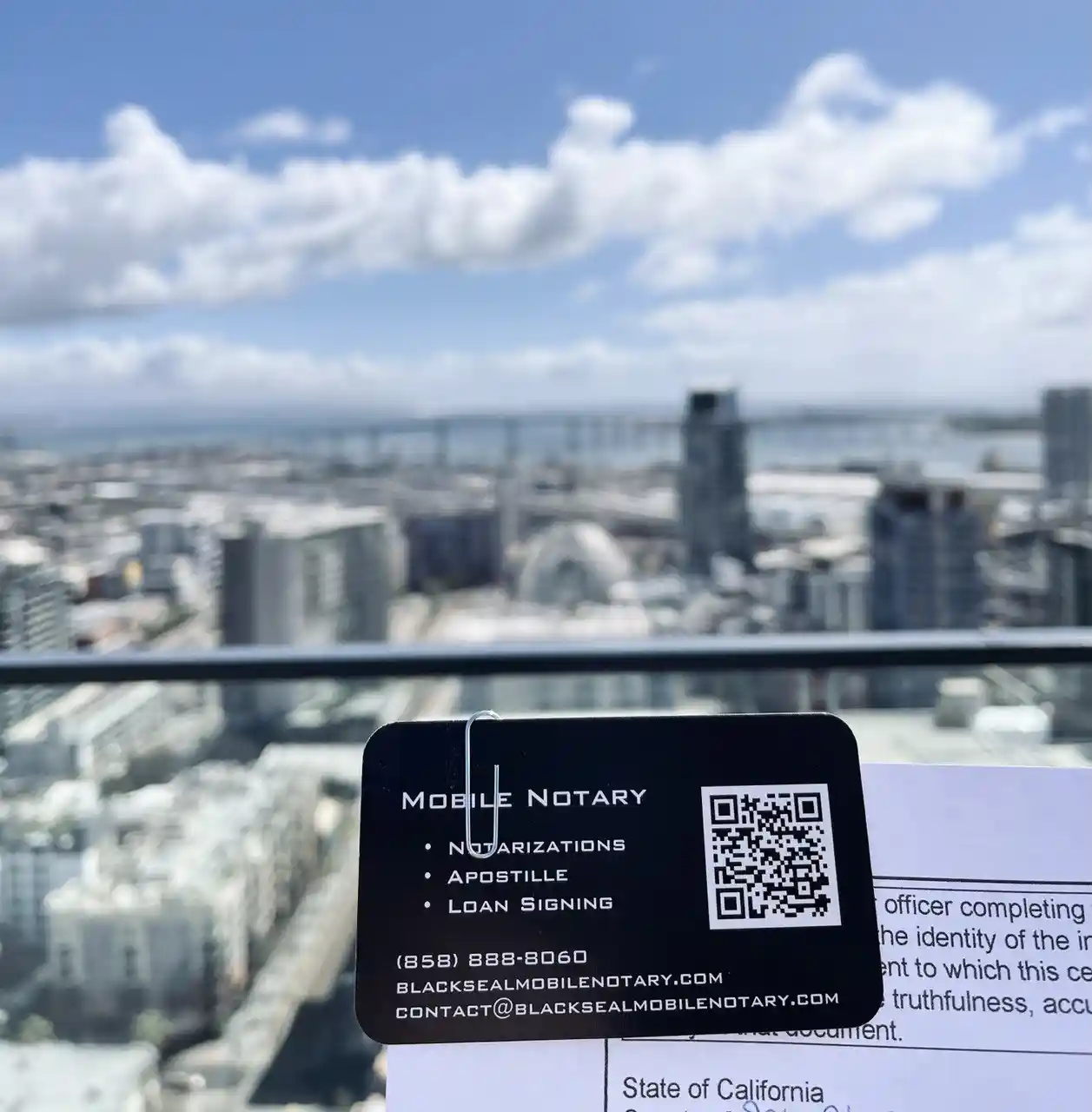 Black Seal Mobile Notary card held above the downtown San Diego skyline and Coronado Bridge